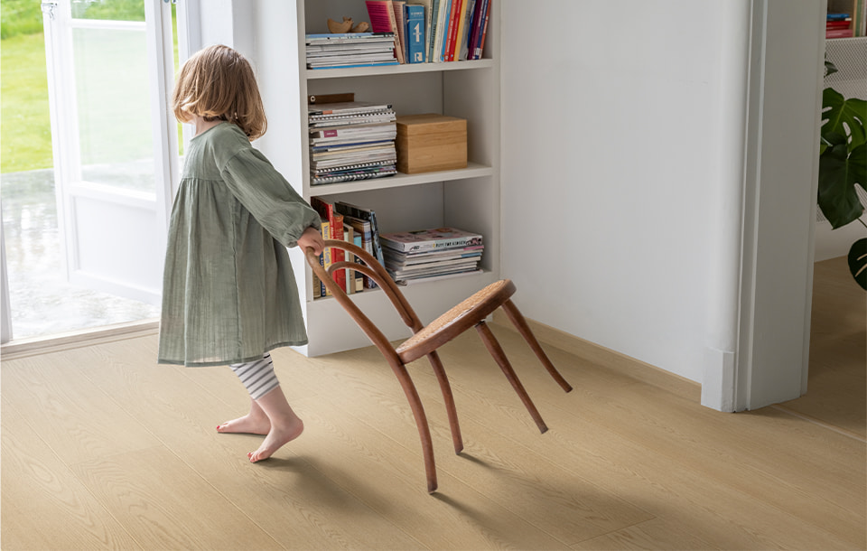 dziecko przeciągające krzesło na beżowej podłodze laminowanej